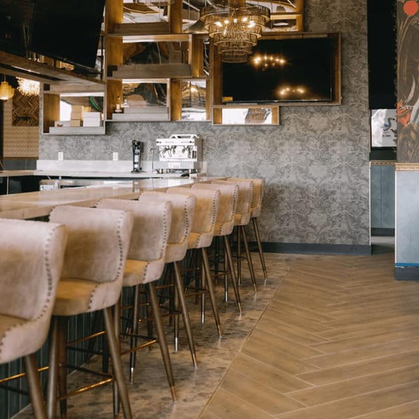 Dodo Bird Kitchen and Cocktails bar area with light-colored bar stools and a patterned wall.