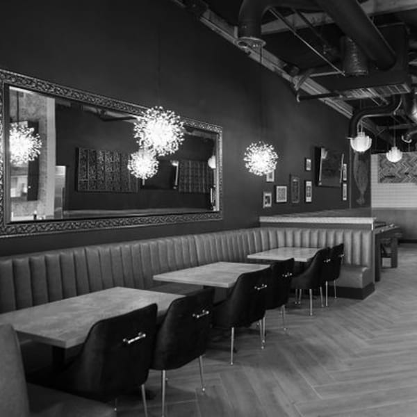 Interior of Dodo Bird Kitchen and Cocktails, showing dining tables, chairs, and booth seating.