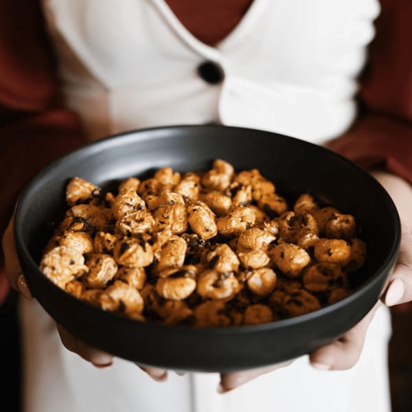 Hands holding a black bowl filled with Dodo Bird Kitchen and Cocktails' seasoned popcorn.