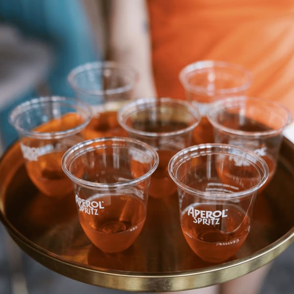 A tray of six plastic cups filled with orange Aperol Spritz cocktails at Dodo Bird Kitchen and Cocktails.