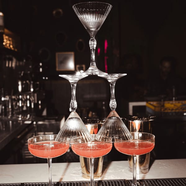 A cocktail pyramid of coupe glasses filled with red drinks, stacked on a bar at Dodo Bird Kitchen.
