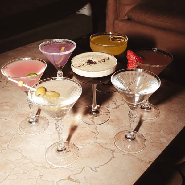 A variety of colorful cocktails, including martinis and an espresso martini, on a marble table.
