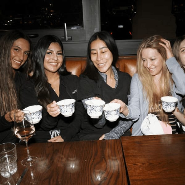Five women smiling and holding small patterned cups at Dodo Bird Kitchen and Cocktails.