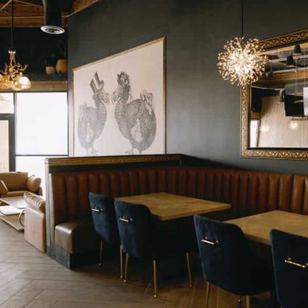 Interior of Dodo Bird Kitchen and Cocktails with brown booths, dark blue chairs, and dodo bird artwork.