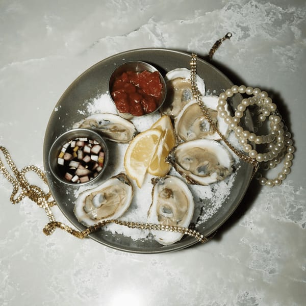 Oysters on a bed of salt with lemon, cocktail sauce, and mignonette, adorned with jewelry.