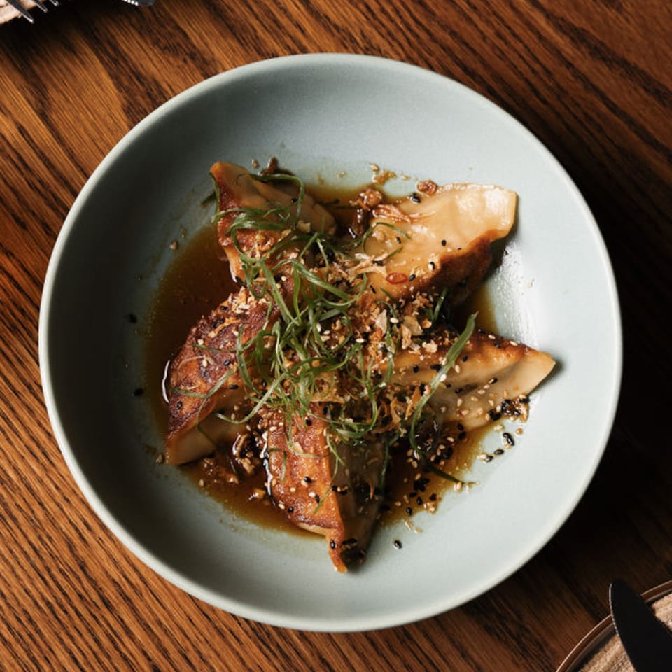 Dodo Bird Kitchen and Cocktails' braised mushrooms with sesame seeds and green onions in a light blue bowl.
