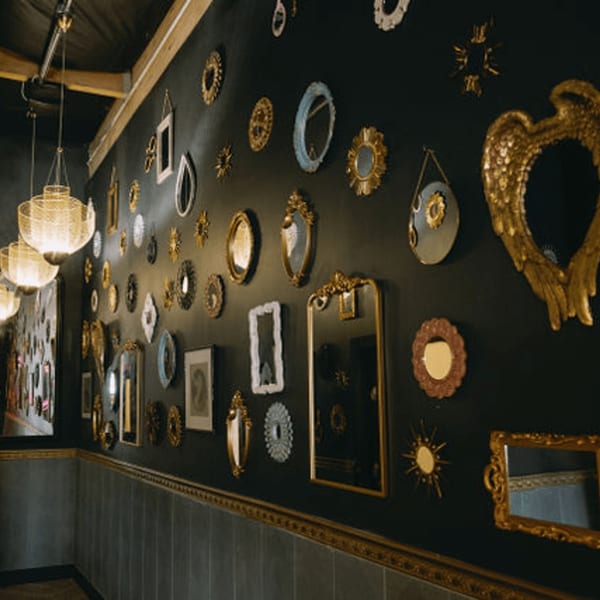 A dark wall at Dodo Bird Kitchen and Cocktails adorned with an eclectic collection of ornate mirrors.