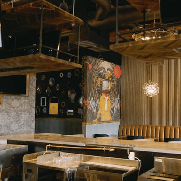 Dodo Bird Kitchen and Cocktails' bar area with unique artwork, modern lighting, and booth seating.