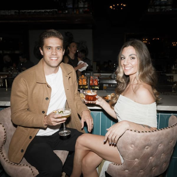 Smiling couple enjoying cocktails at the Dodo Bird Kitchen and Cocktails bar.