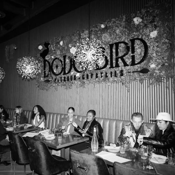 Diners seated at tables in Dodo Bird Kitchen and Cocktails, with a large Dodo Bird sign.